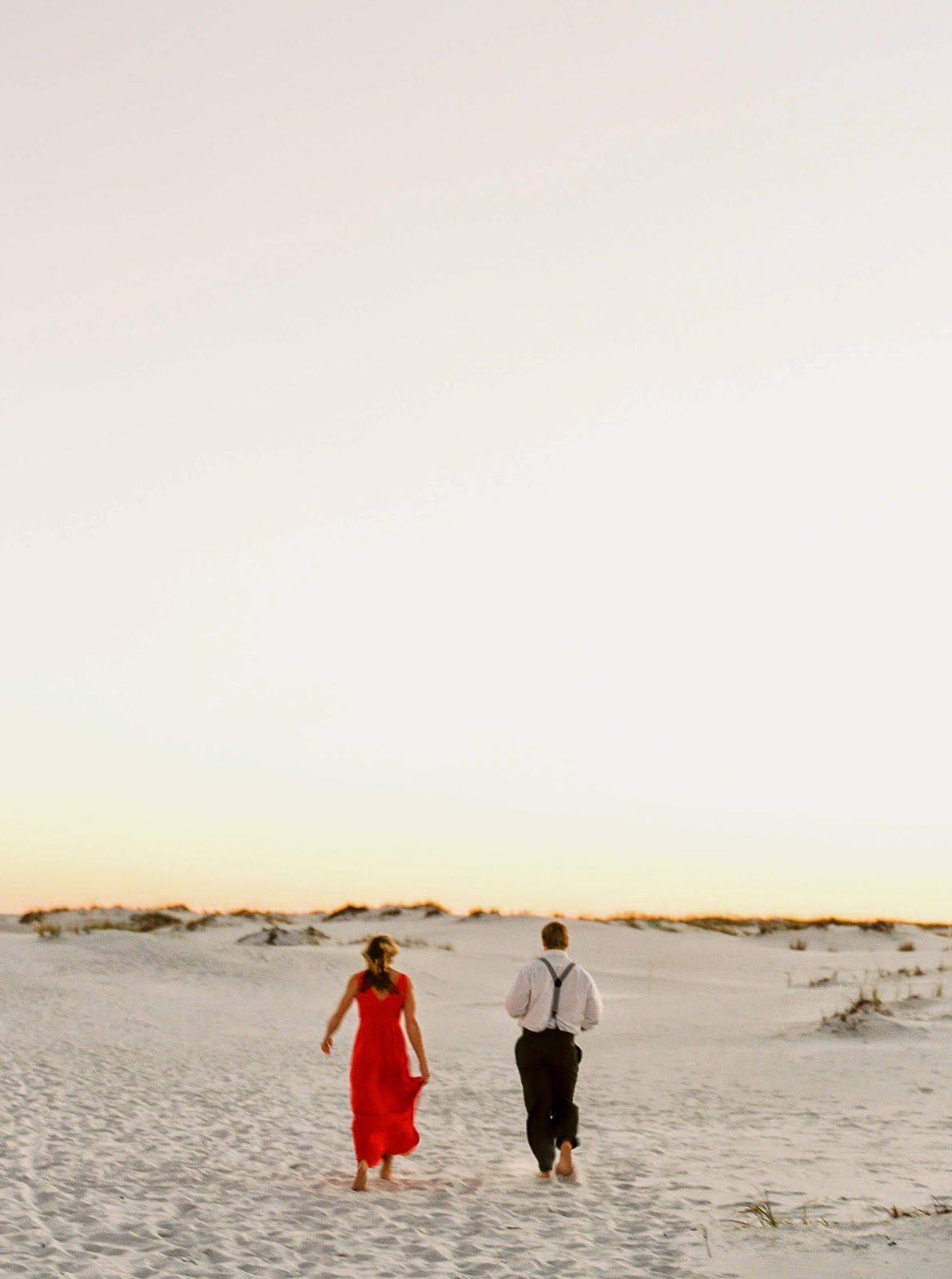 A couple runs on the beach in Destin, Florida as the sun sets.