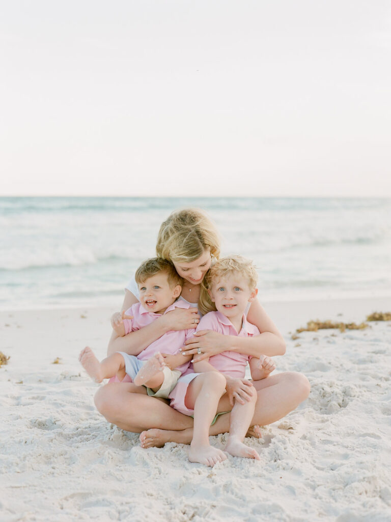 A mother holding her baby boys on the beach in Rosemary Beach. 