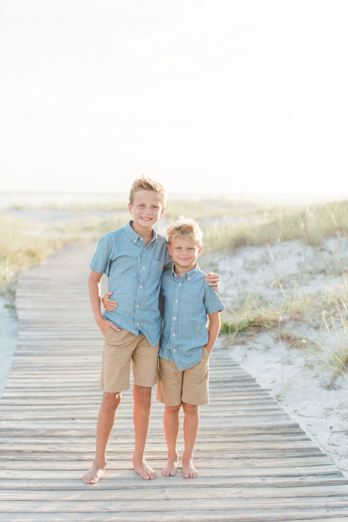 Two brothers walk on the boardwalk in 30A during sunset. 
