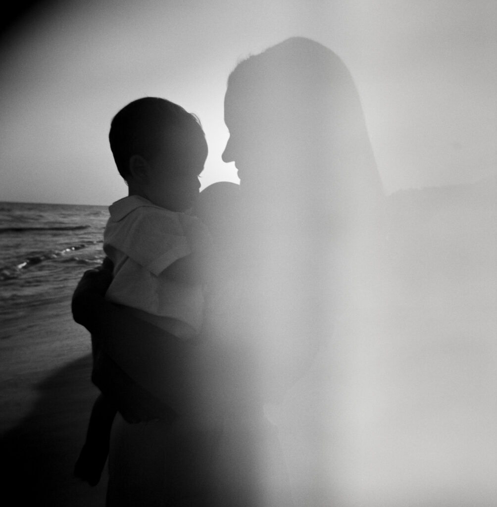 A mother holds her son close while looking down at him as the sun sets in Alys Beach, Florida.
