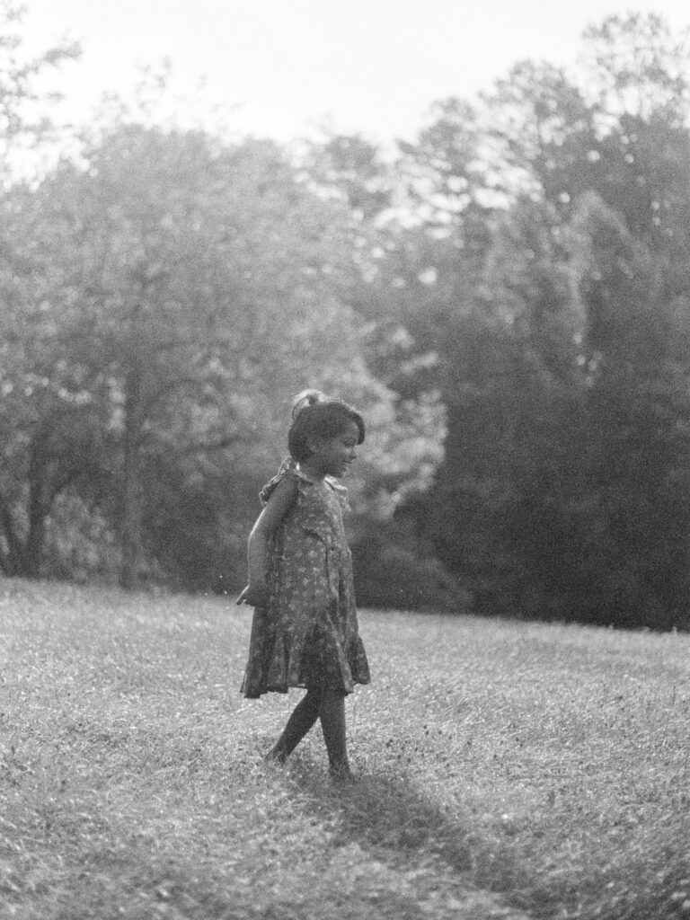 An indian little girl runs down a grassy hill barefoot in her Jamie Kay dress.