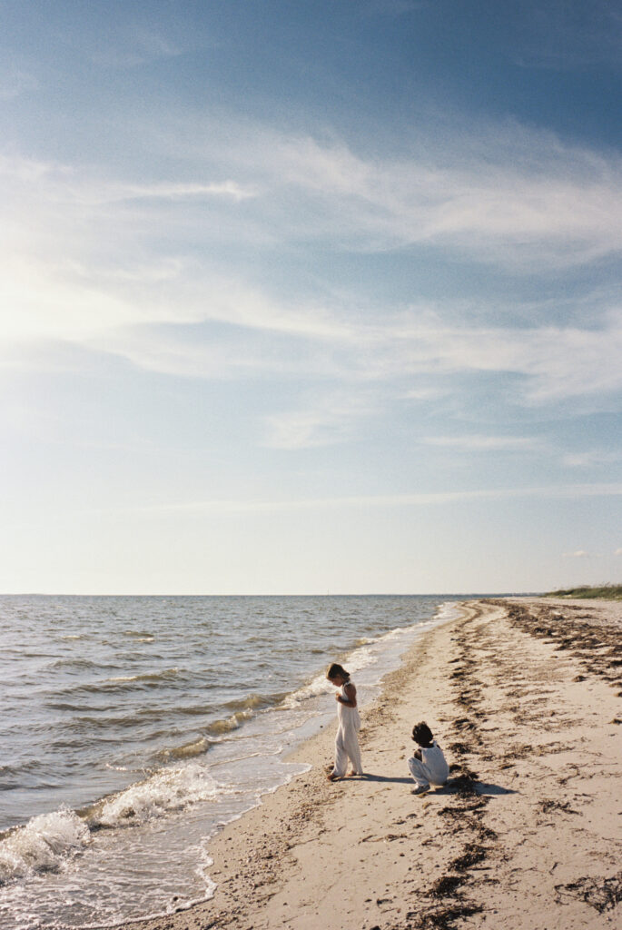 Two sisters walk along the shoreline picking up seashells on the forgotten coast of florida. 