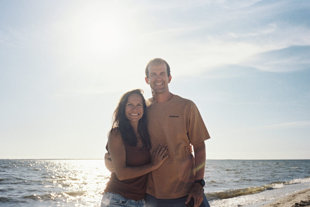 A couple smiles for the camera while walking along the beach on the forgotten coast of florida. 
