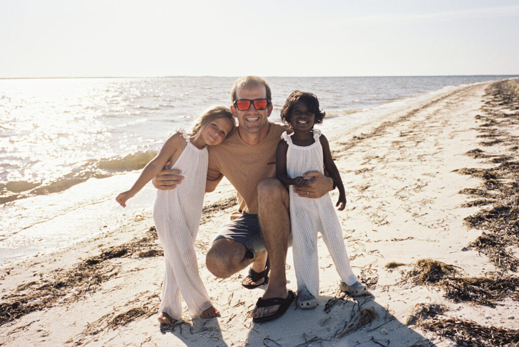 A father with his two daughters walk on the beach in port st joe florida. 
