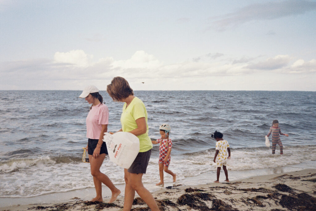 A family walks along the beach with bags in hand to collect shells along the forgotten coast of florida. 
