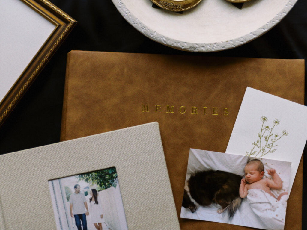 A leather family photo album to organize family photos in along with gold, antique picture frames. 