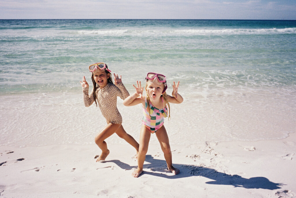 Two little girls making silly faces on the beach in 30A.