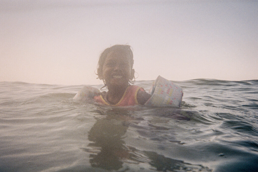An indian little girl swims with floaties on in the Gulf of Mexico in 30A.