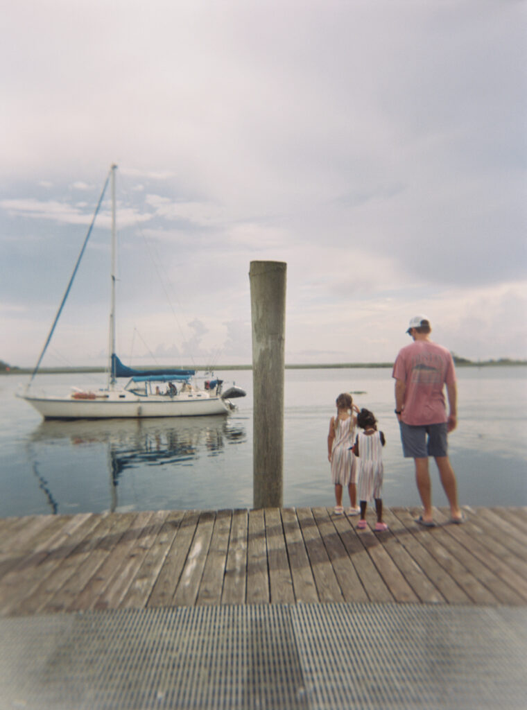 A man with his two daughters look out on a passing boat at the Apalachicola marina. 