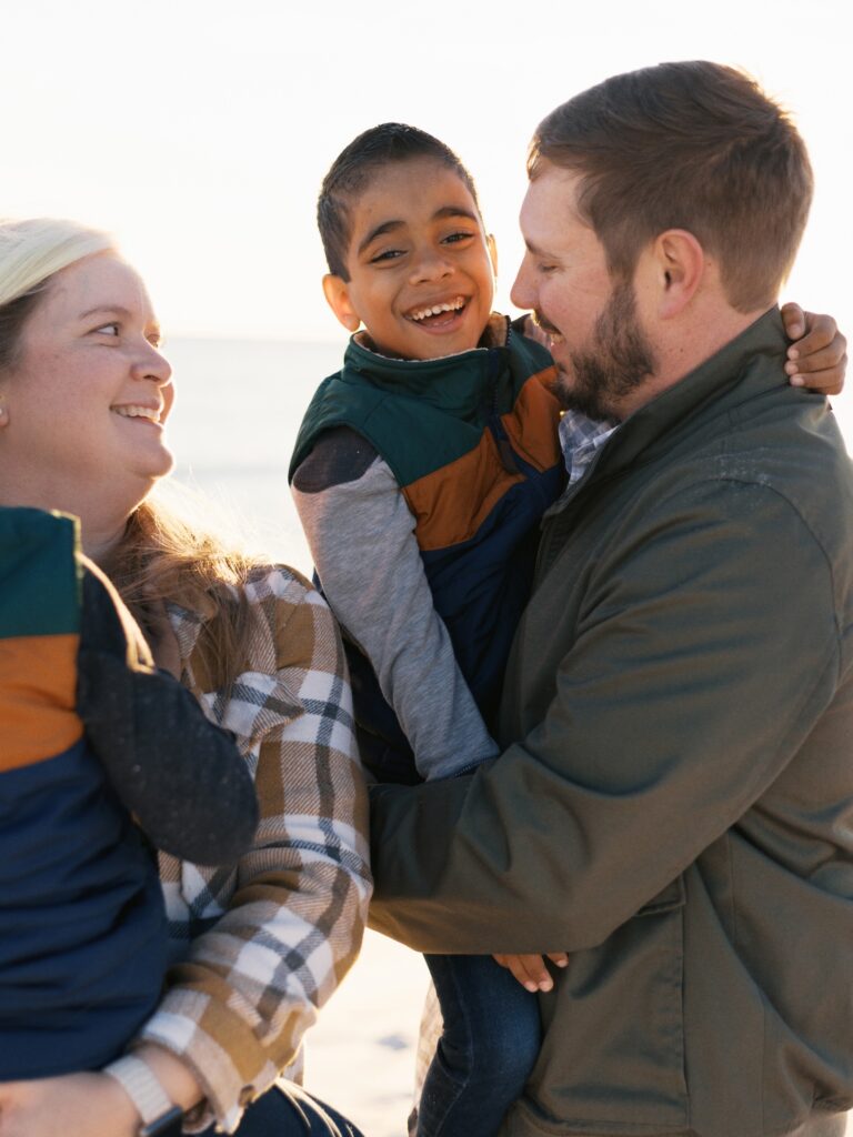 A family smiles on the beach while watching the sun set in Destin, FL. 