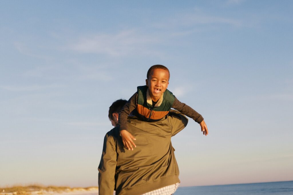 A father carries his son on his shoulders on the beach in Destin, FL. 