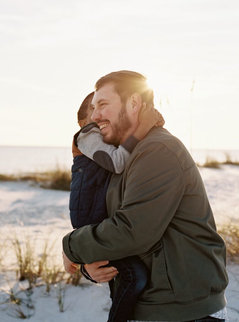 A father and his son laugh during sunset in Destin, FL. 